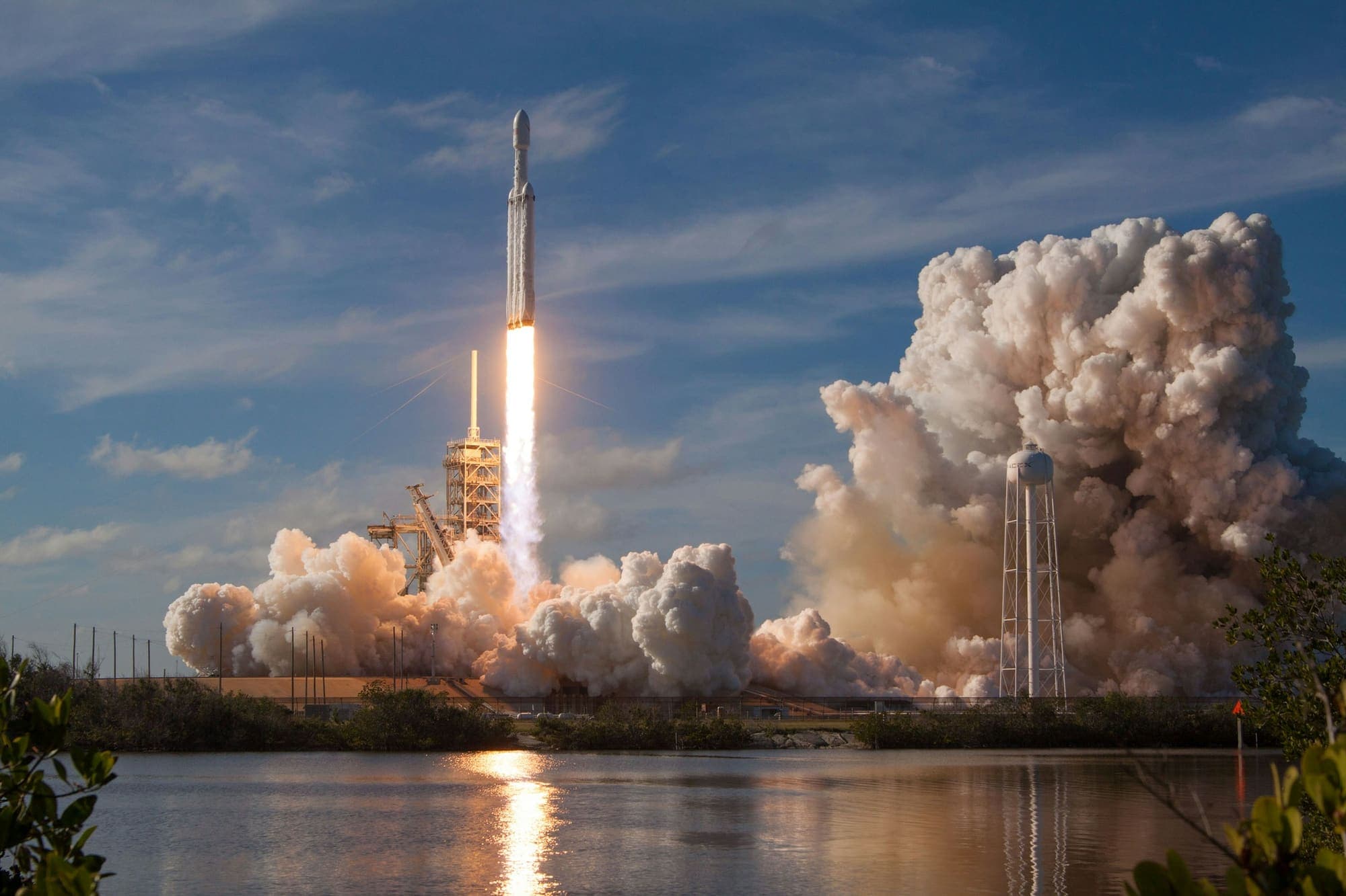 Heavy-lift rocket lifting off past its launch tower
